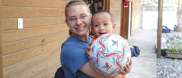 student and child with soccer ball